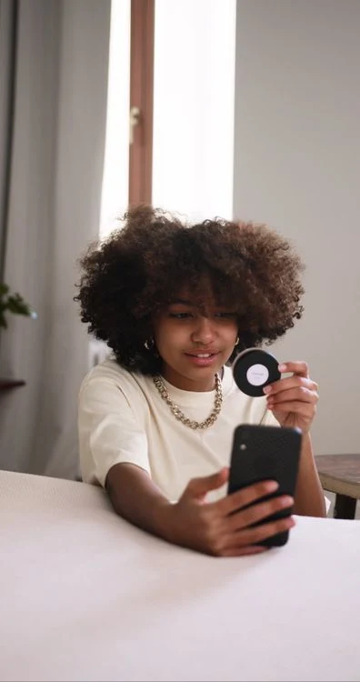 A beauty creator holding a makeup compact while filming a product review.